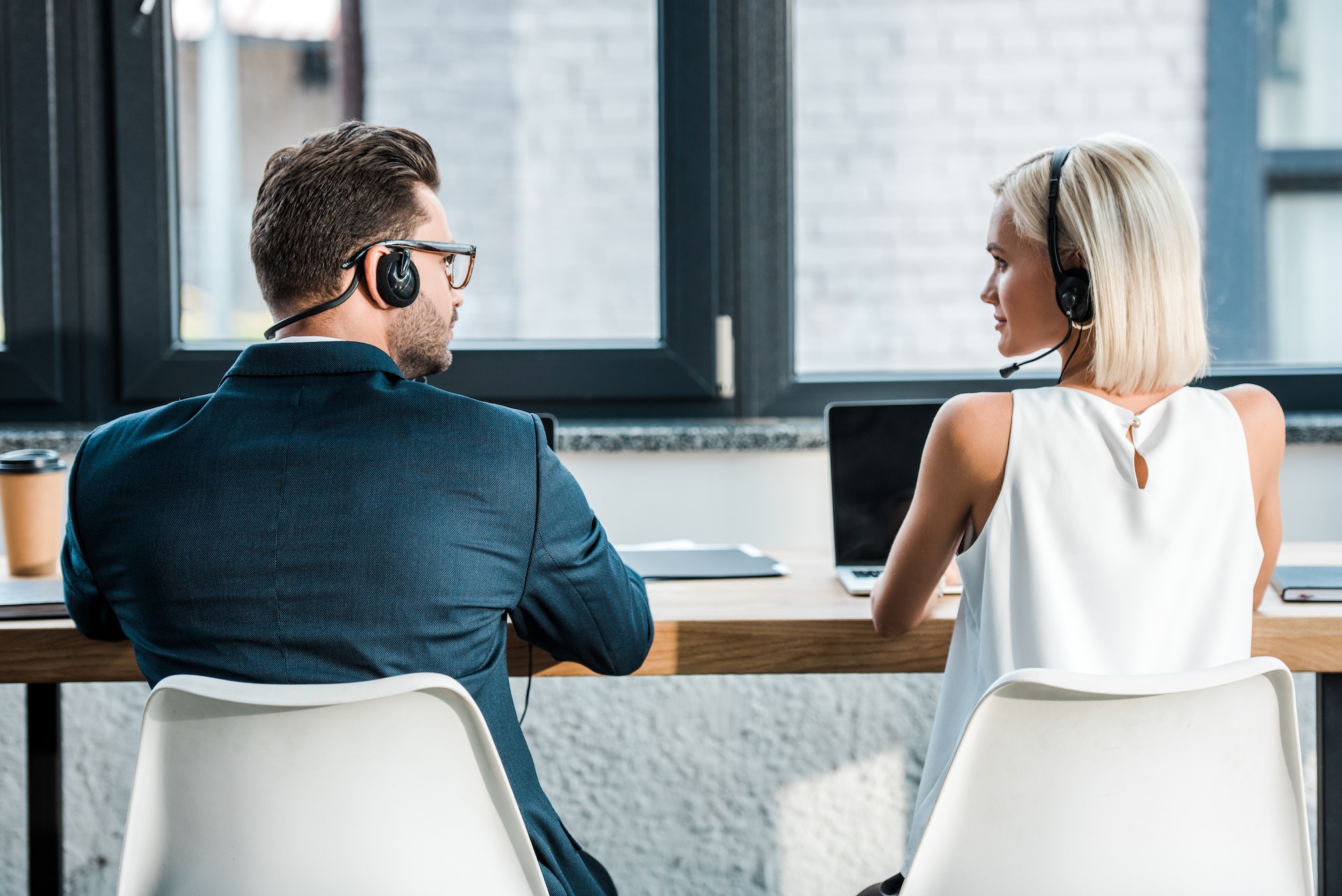 operators in headsets looking at each other while sitting in office